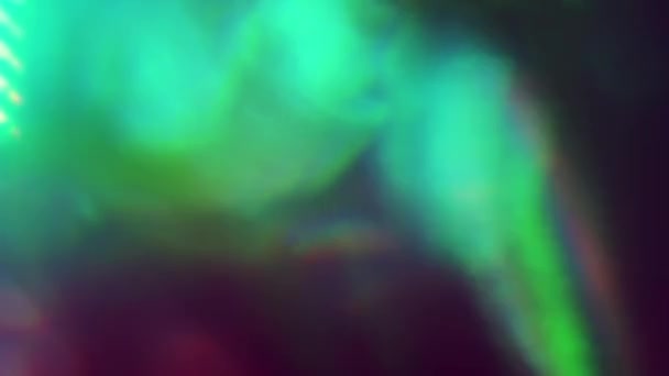 Πολύχρωμες ιριδίζουσες ακτίνες φωτός λάμπουν στο σκοτάδι. Αφηρημένες σταγόνες, επικάλυψη βίντεο. — Αρχείο Βίντεο