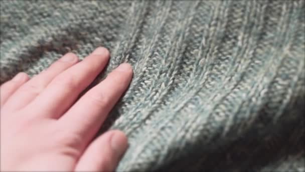 Αρσενικό χέρι που αγγίζει ένα λείο πράσινο πουλόβερ σε ένα κατάστημα υφασμάτων. Κοντινό πλάνο. — Αρχείο Βίντεο