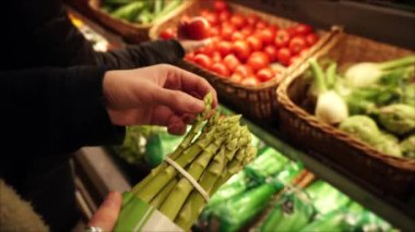 Vejetaryen kız yerel süpermarkette taze organik kuşkonmaz bir demet seçer.