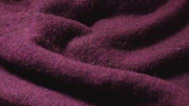 Bir tekstil mağazasında bordo renkli sentetik kazak detaylı çekim. 