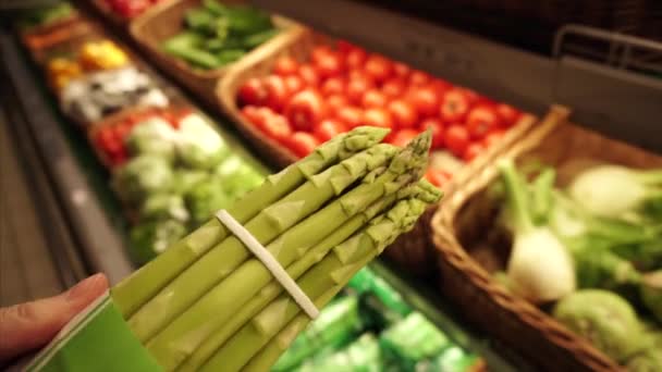 El comprador selecciona un montón de espárragos orgánicos frescos en el supermercado local . — Vídeos de Stock