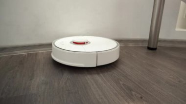 Akıllı modern elektrikli süpürge masanın altındaki laminat ahşap zemini temizler .