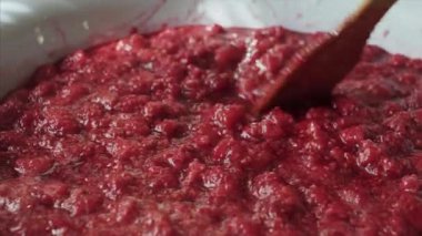 Ahşap bir spatula ile emaye bir kase içinde ahududu reçeli karıştırarak Kadın.
