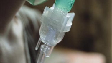 Aerosol nebülizör inhaler kullanarak bronşitli kadının yakından görünümü.