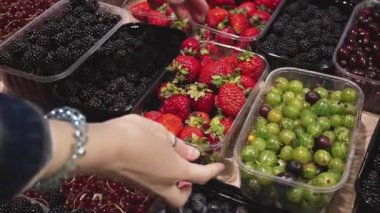 Genç bakım anne süpermarketin bakkal bölümünde bektaşi üzümü seçimi. 