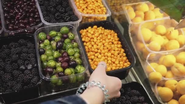 Una donna sceglie olivello spinoso sul bancone del negozio al supermercato . — Video Stock