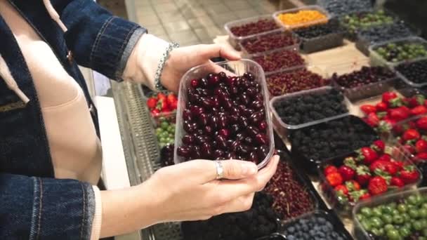Вегетаріанська жінка вибирає корнеліан вишня в супермаркеті. — стокове відео