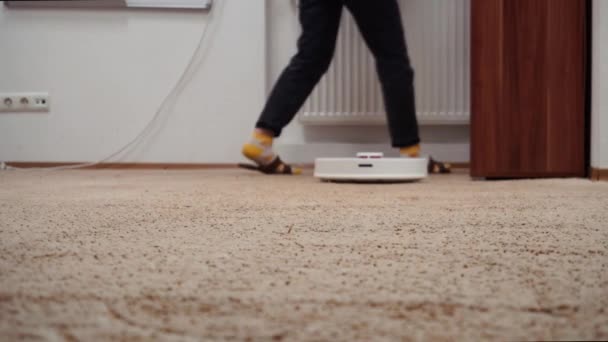 De huisvrouw boel in de speelkamer. De robot stofzuiger reinigt het tapijt. — Stockvideo