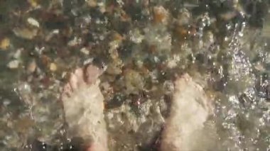 Mans ayakları deniz dalgaları yla yıkandı. Üst te. Yakın çekim.