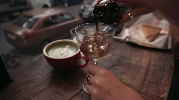 La fille verse du café froid dans un verre de glace dans un café le soir . — Video