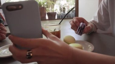Kız blogger lavanta makarna yiyor ve birine bir akıllı telefon ekranı gösterir.