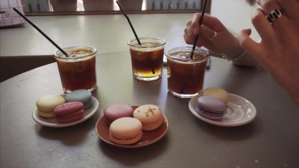 Close up de uma menina come macaron francês e bebe espresso bebida tônica . — Vídeo de Stock