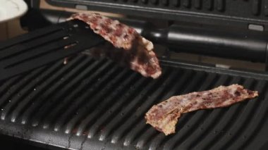 Kadın ızgara bitmiş sulu pastırma et alır.