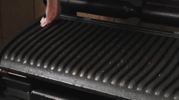 Kvinnan lägger färsk bacon på en elektronisk hem grill. — Stockvideo