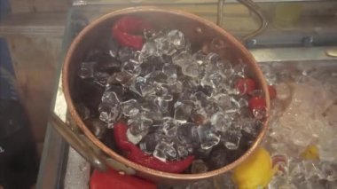 Lokanta tezgahında buz ve biberin içinde soğuk taze midyeler..