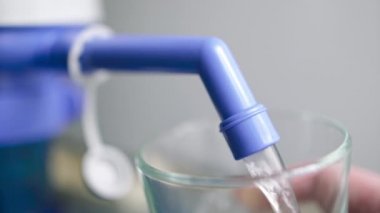 Ev ve ofis kullanımı için el yapımı su dağıtıcısından bardağa su dökülür..