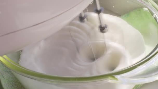 Close-up of metal whisks of a hand mixer whipps egg whites with sugar syrup. — Stock Video