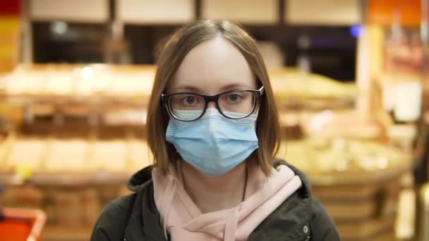 Kvinna i skyddande medicinsk mask och glasögon. Porträtt. slow motion i snabbköpet, närbild. — Stockvideo