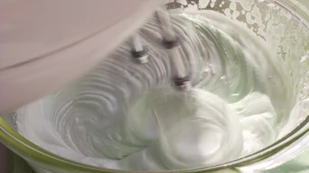 Os batedores metálicos de um misturador de mão chicoteam brancos de ovo com o xarope de açúcar. Cozinhar merengue italiano em casa . — Vídeo de Stock