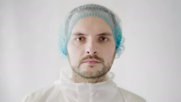 Portrét mužského lékaře virologa, zdravotnického personálu v ochranném obleku a lékařské čepice na bílém podkladě. — Stock video