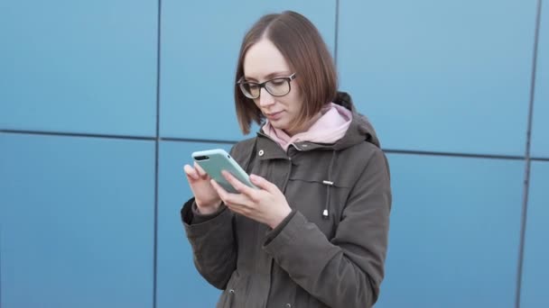 Atraktivní běloška dívka hipster student v brýlích pomocí smartphonu. — Stock video