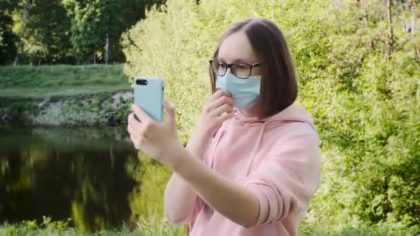 The girl takes off her protective mask and takes a selfie on smartphone for social media. — Stock Video