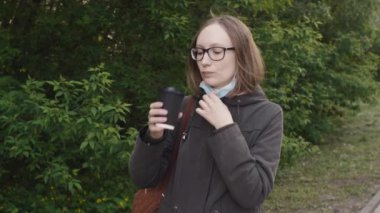 Koronavirüs salgını sırasında kız maskesini çıkarıyor ve kahve içiyor..