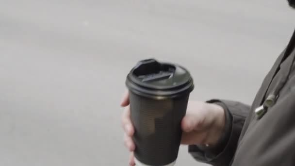 Primer plano de la mano femenina con café para llevar mientras camina por la ciudad . — Vídeos de Stock