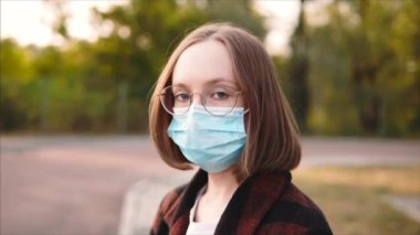 Tıbbi maske takmış ve gözlüklü 20 'li yaşlarda bir kadının portresi..