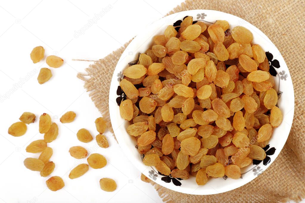 Bowl with dried golden raisins isolated on white. Dried Grapes.
