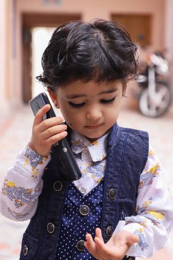 Tatlı Hintli çocuk konuşuyor ve cep telefonuyla oynuyor..