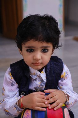 Sevimli Hintli çocuk kucağında topu tutuyor.