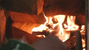 Yaşlı kadının elinde bir günlük yanan şöminede koymak.