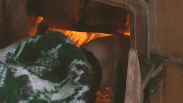 Les vieilles mains de femmes ont mis une bûche dans la cheminée en feu .