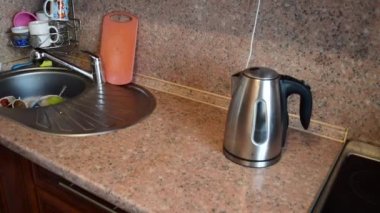 Çağdaş mutfağın modern elektrikli çaydanlığını açan güzel bir kadın..