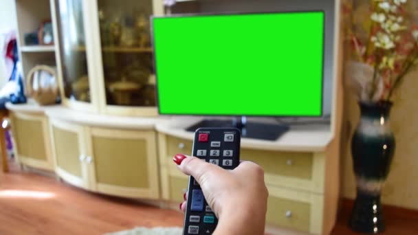 緑の画面でテレビのリモートスイッチングチャンネルを持つ女性の手テレビの視点 — ストック動画