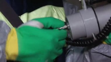 Tehlikeli madde ekipmanlı bir adam terk edilmiş fabrikada laboratuvar malzemelerini alıyor. İçeride. Yakın çekim.