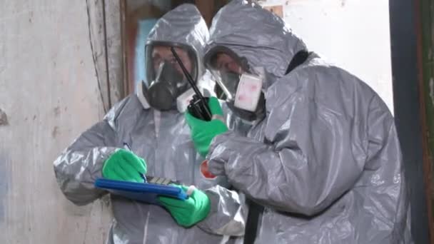 ハズマットの服を着た男が研究室のために物事を取る 放棄された工場で2人の化学者が — ストック動画