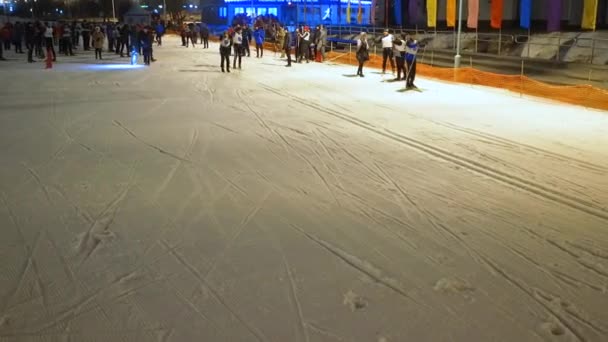 Vista aérea: Los esquiadores bajan por la ladera en la noche de invierno. competición de esquí — Vídeo de stock