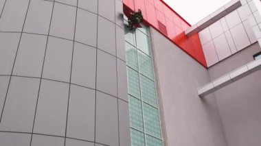 03.12.2019 Minsk Belaus. İtfaiyeci camdan bir binanın ön cephesinde iple asılıyor.