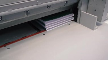 Matbaa işçisi kesme makinesi kullanıyor. İşçi tipografide bir yığın kağıt kesiyor.