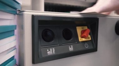 Matbaa işçisi kesme makinesi kullanıyor. İşçi tipografide bir yığın kağıt kesiyor.