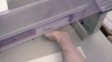 Matbaa işçisi kesme makinesi kullanıyor. İşçi tipografide bir yığın kağıt kesiyor.
