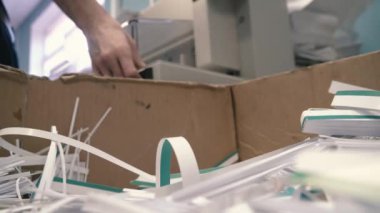 Matbaa nın işçisi kağıt atıkları için kutuya atık kağıt şeklinde çöp atar.