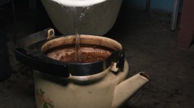 Yaşlı adam kovadan su ısıtıcısı doldurma