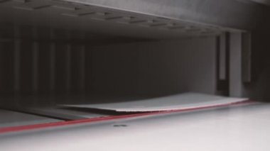 Matbaa işçisi kesme makinesi kullanıyor. İşçi tipografide bir yığın kağıt kesiyor.