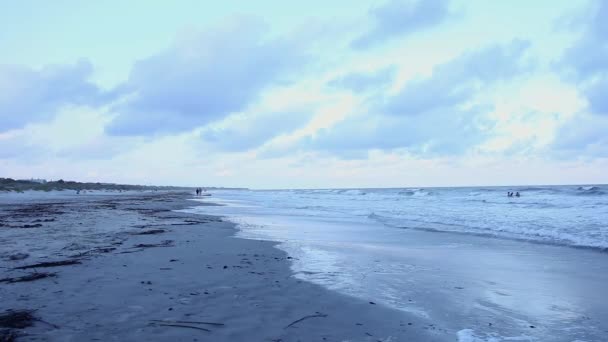 Vågor svagt kraschar på en sandstrand som solen går ner över horisonten — Stockvideo