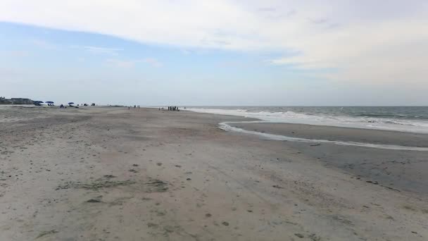 Vågor svagt kraschar på en sandstrand som solen går ner över horisonten — Stockvideo