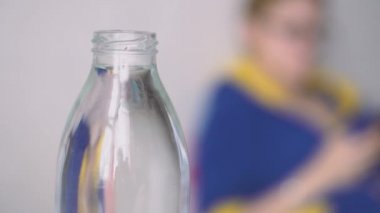 Genç kadın evde su şişesi içiyor. 4k