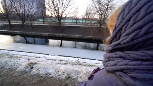 Bellissimo tramonto, bella ragazza passeggiando lungo il molo nel porto, e guardando il tramonto, il cielo si riflette nell'acqua, ghiaccio primaverile sciogliersi sull'acqua, vacanza, fuori città. 4k — Video Stock